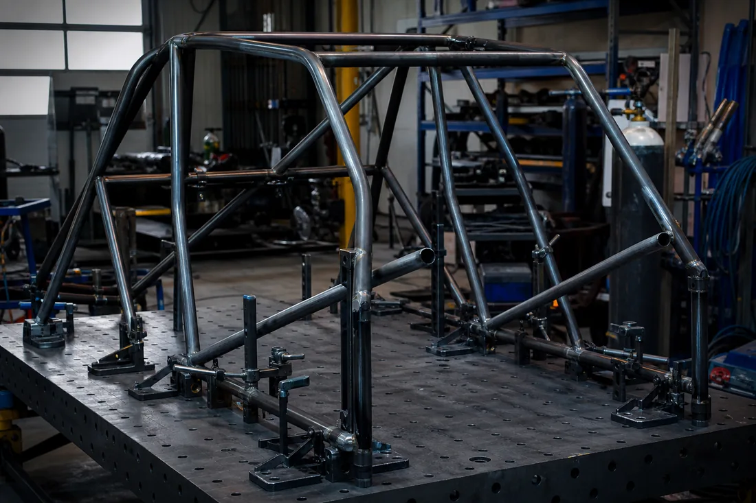 Tubular steel roll cage clamped on a welding jig at the Telhoo workshop
